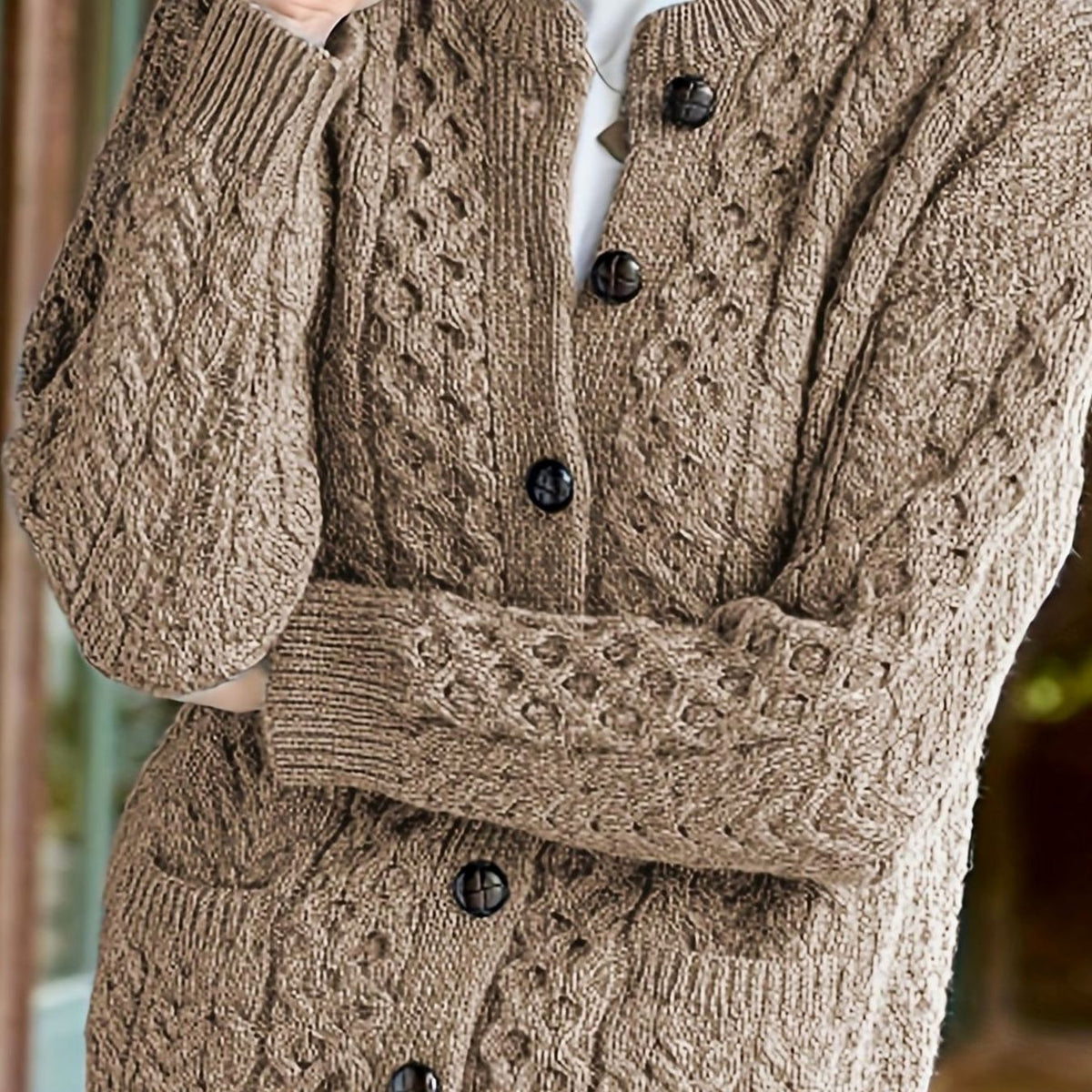 Kabelstrikket cardigan med knapper lagt frem